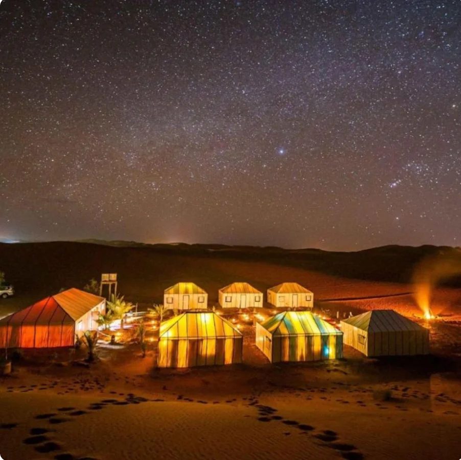Campo tendato illuminato sotto le stelle nel Sahara